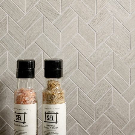 Dos botellas de especias se apoyan contra una pared de azulejos en forma de espiga de color gris claro. El texto en las botellas Dos botellas de especias se apoyan contra una pared de azulejos en forma de espiga de color gris claro. El texto en las botellas