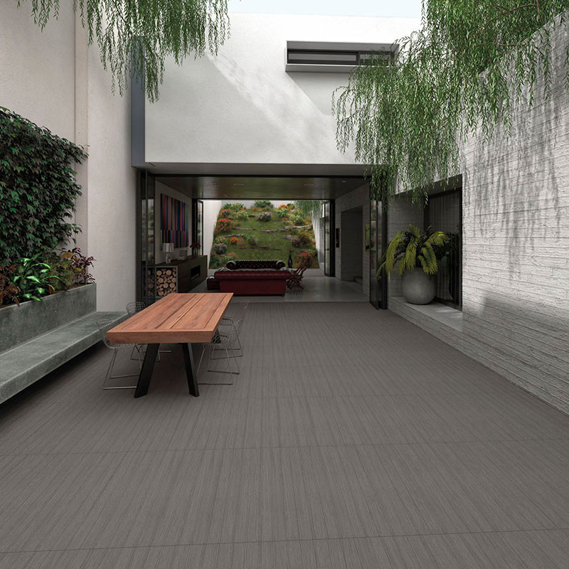 Una mesa rectangular de madera, rodeada de sillas transparentes, se encuentra en un patio moderno con vegetación colgando encima