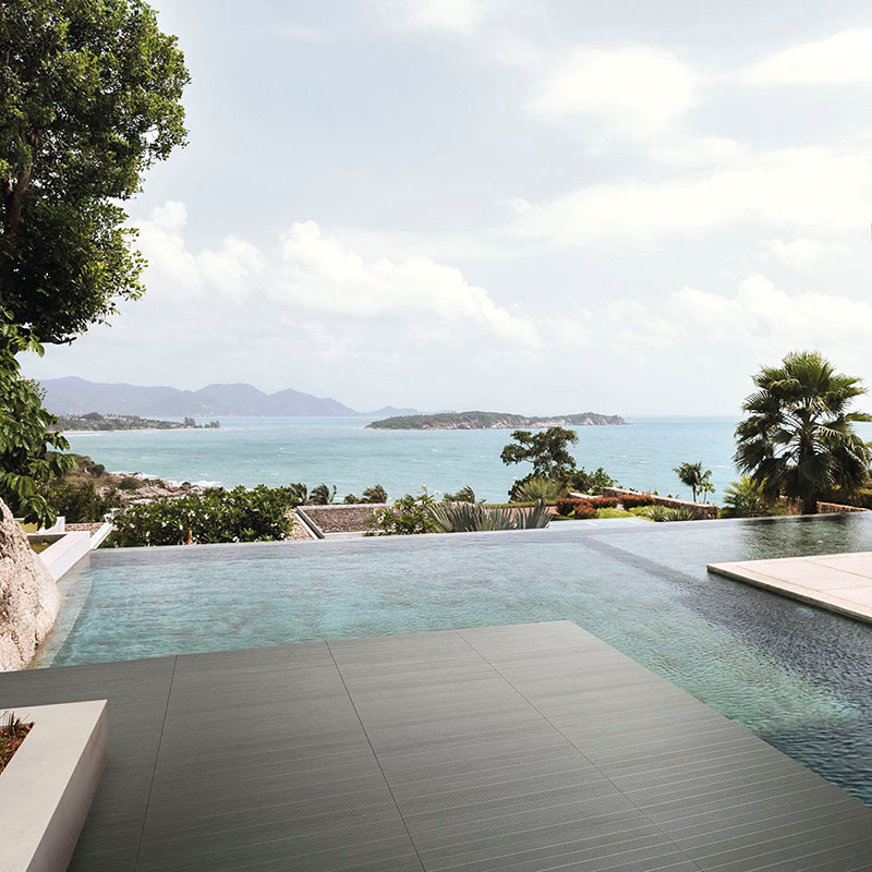 Une piscine à débordement moderne s'étend harmonieusement vers un océan serein, entouré d'une verdure luxuriante et d'îles loint
