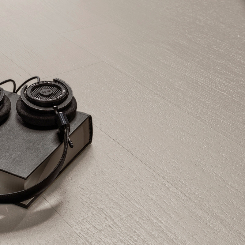 Los auriculares descansan sobre un libro negro cerrado, colocado sobre un piso o Azulejo texturizada de color claro, creando un 