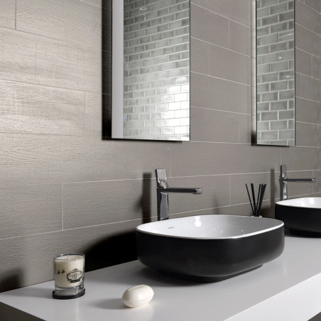 Een moderne badkamergootsteen bevindt zich in een strak aanrechtblad, vergezeld van een stuk zeep en een kaars, tegen een grijs 