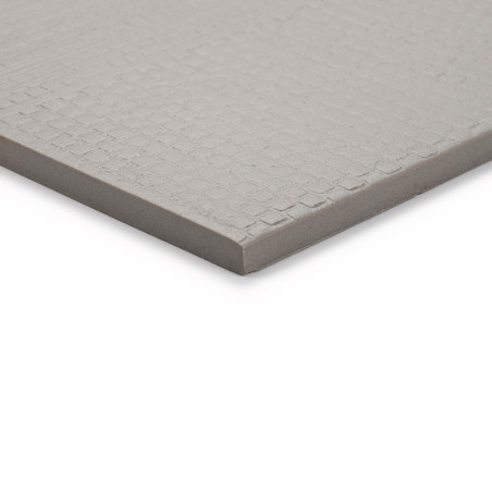 Een vierkante, grijze keramische tegel met een subtiel structuurpatroon rust tegen een effen witte achtergrond en laat de gladde