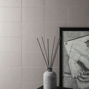 Een parfumflesje met uitstekende uitstekende stokjes staat op een donker oppervlak, naast een ingelijste monochrome tekening, te