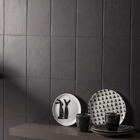 Dunkle, strukturierte Fliesen bilden eine moderne Wand. Auf einem Holzregal stehen Teller mit minimalistischen Hasen- und Dreiec