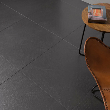 Ladrilhos quadrados cinza escuro formam um piso liso. Uma cadeira de couro marrom fica perto de uma mesa lateral redonda de made Ladrilhos quadrados cinza escuro formam um piso liso. Uma cadeira de couro marrom fica perto de uma mesa lateral redonda de made