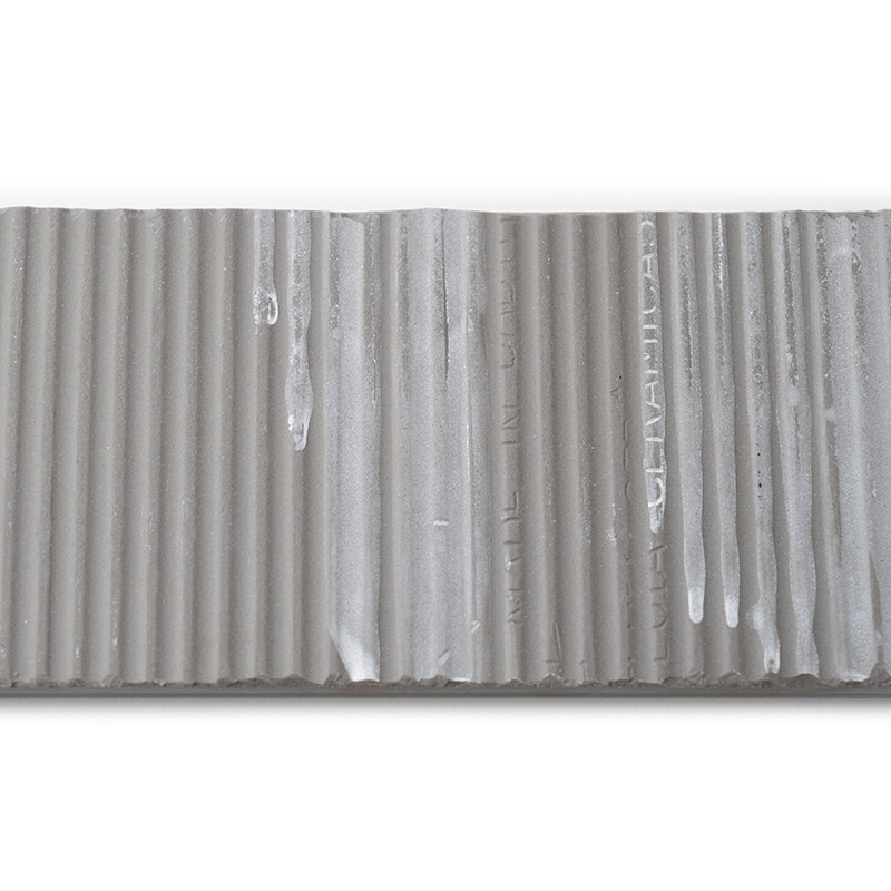 El azulejo es una franja rectangular con crestas verticales y presenta el texto impreso: `MADE IN ITALY, CERAMICA`. Su superfici