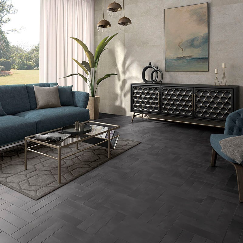 Un carrelage gris à chevrons recouvre le sol du salon, entouré d'un canapé bleu, d'une table basse en verre et d'œuvres d'art ab