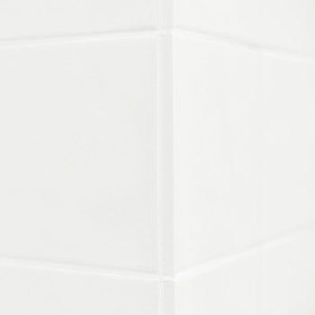 Witte keramische tegels vormen een strakke hoek en reflecteren het licht op subtiele wijze. Het gladde oppervlak suggereert een 