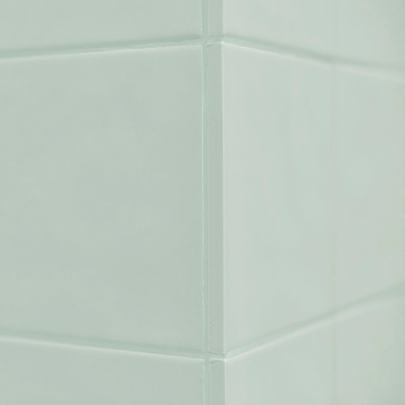 A light green ceramic tile forms a corner with clean, straight grout lines meeting at a right angle, creating a seamless, smooth