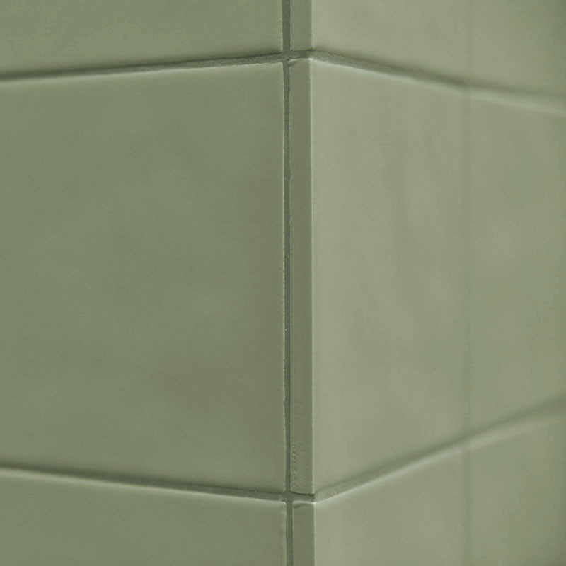Los azulejos de cerámica verde forman una esquina, creando una superficie limpia y lisa en un ambiente interior minimalista.