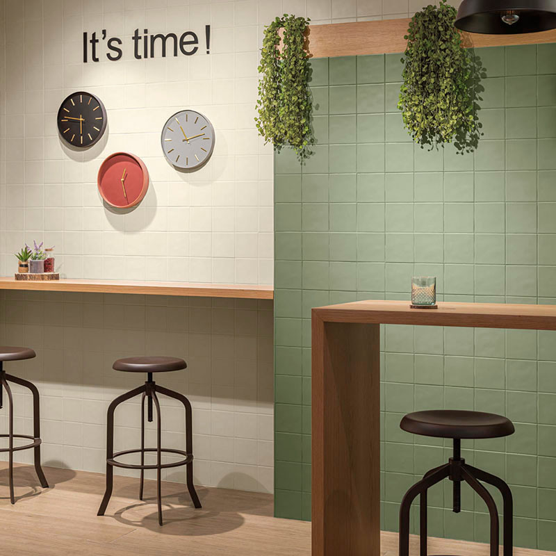 Stools sit at wooden counters in a tiled room with hanging plants. Three clocks adorn the wall, reading: `Its time!`