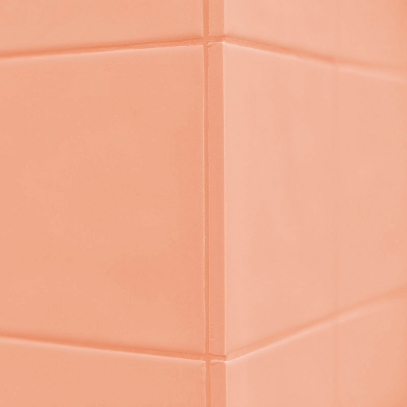 Les carreaux de couleur pêche forment un motif de coin, se croisant avec des lignes de coulis épurées, créant une surface murale