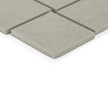 Grijze vierkante tegels rusten op een glad oppervlak, waarbij de ene tegel de andere enigszins overlapt, waardoor een eenvoudige