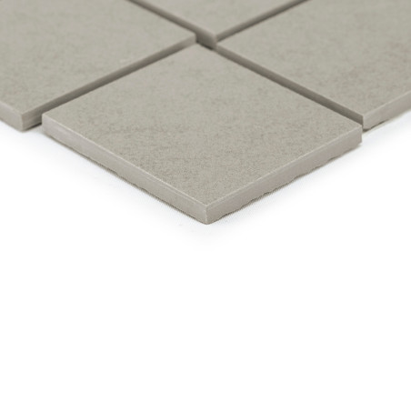 Grijze vierkante tegels rusten op een glad oppervlak, waarbij de ene tegel de andere enigszins overlapt, waardoor een eenvoudige