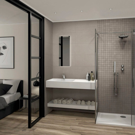 Een moderne badkamer is voorzien van een glazen douchecabine aan de rechterkant, een strakke witte wastafel met toiletartikelen 