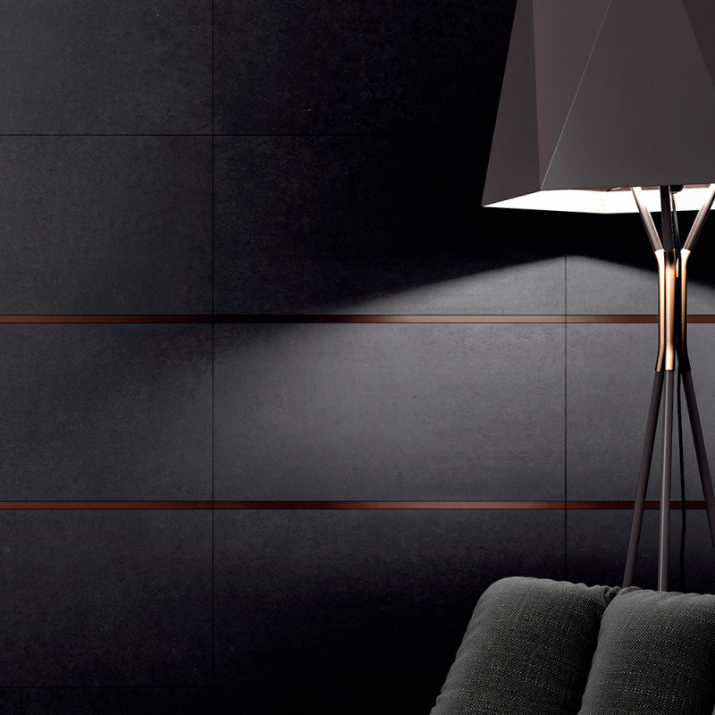 Uma luminária de pé preta ilumina uma parede de azulejos escuros com finas linhas horizontais. Um sofá texturizado aparece parcialmente Uma luminária de pé preta ilumina uma parede de azulejos escuros com finas linhas horizontais. Um sofá texturizado aparece parcialmente