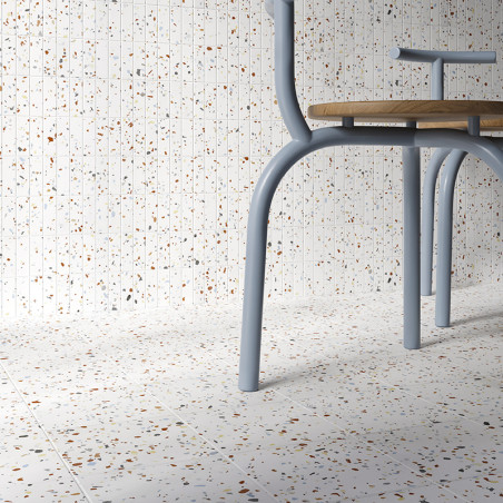 A chair with light blue legs is positioned on a terrazzo-tiled floor featuring colorful specks, against a matching speckled wall