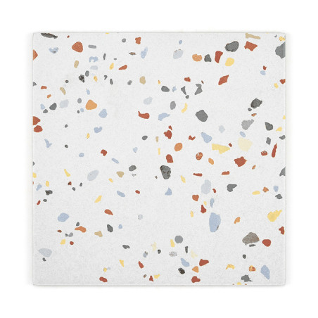 A white ceramic tile displays scattered, colorful specks in red, blue, gray, yellow, and black, creating a terrazzo pattern.