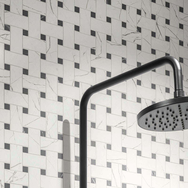 Der Duschkopf erstreckt sich von einem Rohr, das schräg über einer Wand angebracht ist, die mit einem geometrischen Korbgeflecht
