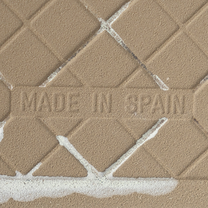 Les carreaux de céramique beige présentent un motif en losanges superposés dans une grille texturée, avec « MADE IN SPAIN » en r