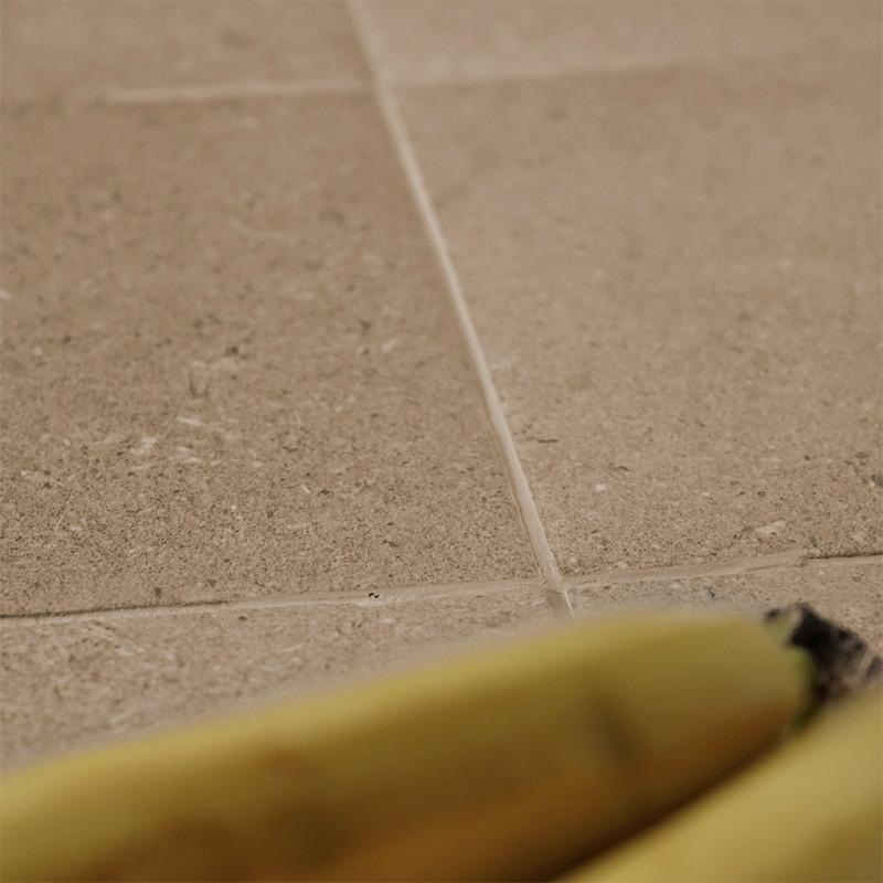 Een banaan rust op stenen tegels en laat een gestructureerd oppervlak en neutrale tinten zien, waardoor een natuurlijke en aards