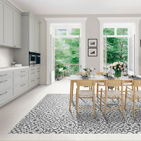 Een eettafel met houten stoelen staat op een grijze en witte tegelvloer met een patroon, omgeven door witte keukenkasten en grot
