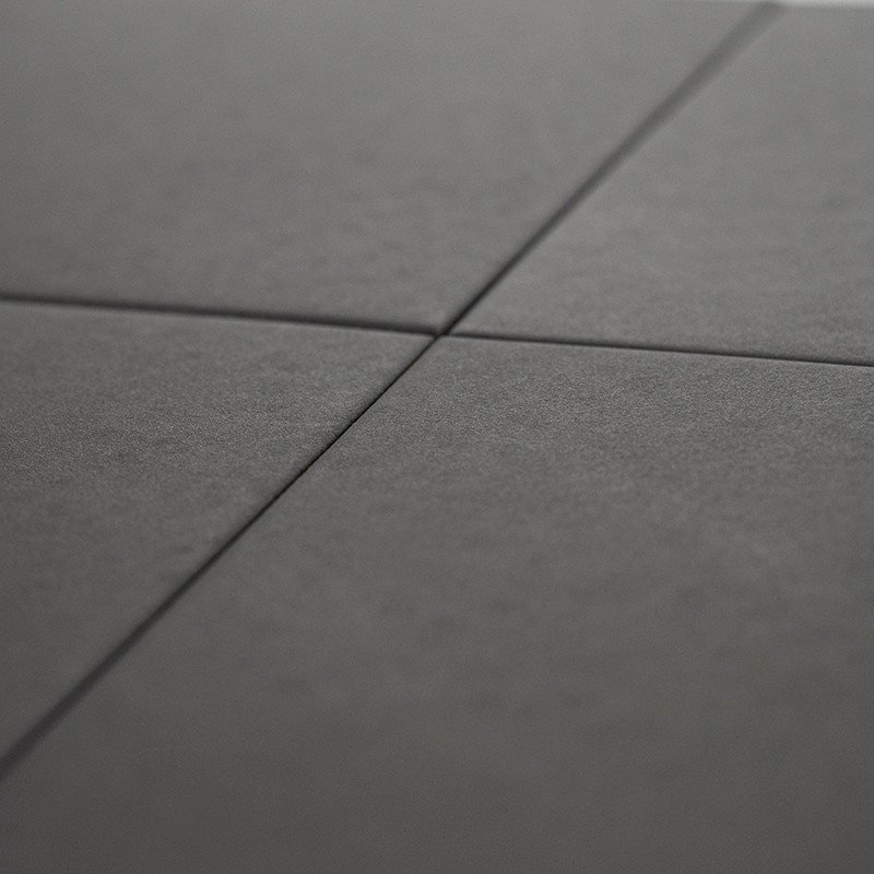 Quatre carreaux carrés gris foncé, disposés selon un motif en grille, se rejoignent en un point central, créant une subtile form