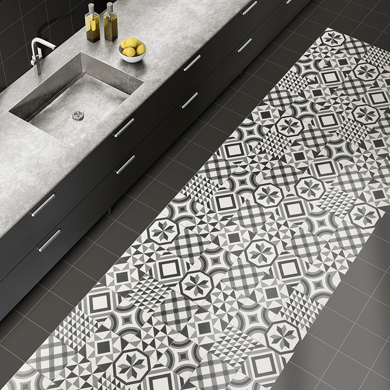 Patterned floor tiles feature geometric black and white designs, adding contrast to a kitchen with a gray countertop and a sink.