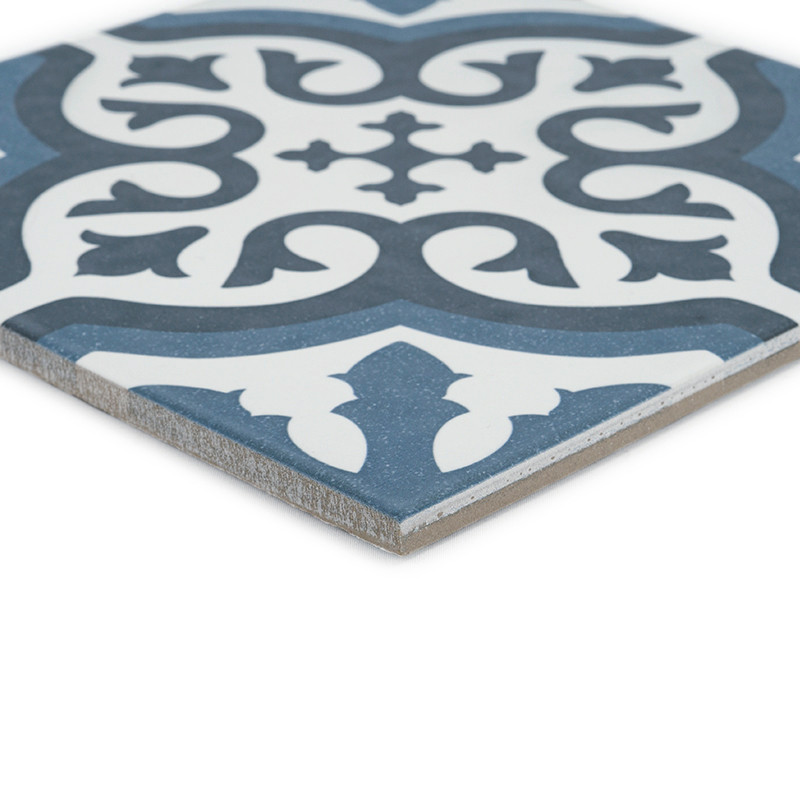 The tile displays an ornate floral pattern in dark blue and white, featuring symmetrical curves and stylized leaves on a square 