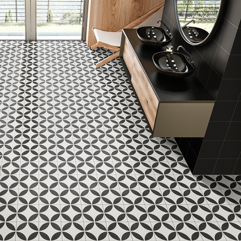 Los azulejos geométricos en blanco y negro cubren el piso del baño con un patrón circular. lavabos y espejos negros se asientan 