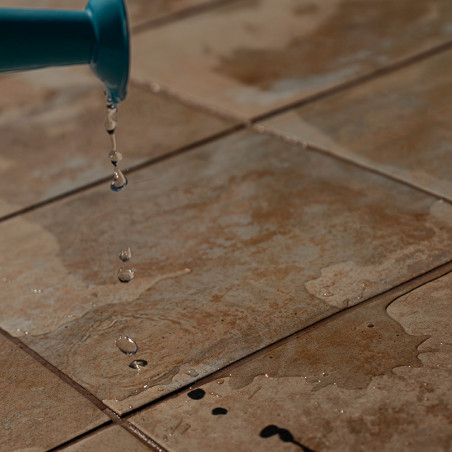 A água pinga de uma bica azul sobre azulejos marrons texturizados, criando pequenas poças e uma superfície molhada em um ambient A água pinga de uma bica azul sobre azulejos marrons texturizados, criando pequenas poças e uma superfície molhada em um ambient