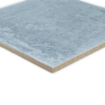 Square ceramic tile with a textured light blue surface, resting flat. The edge reveals a light brown layer.