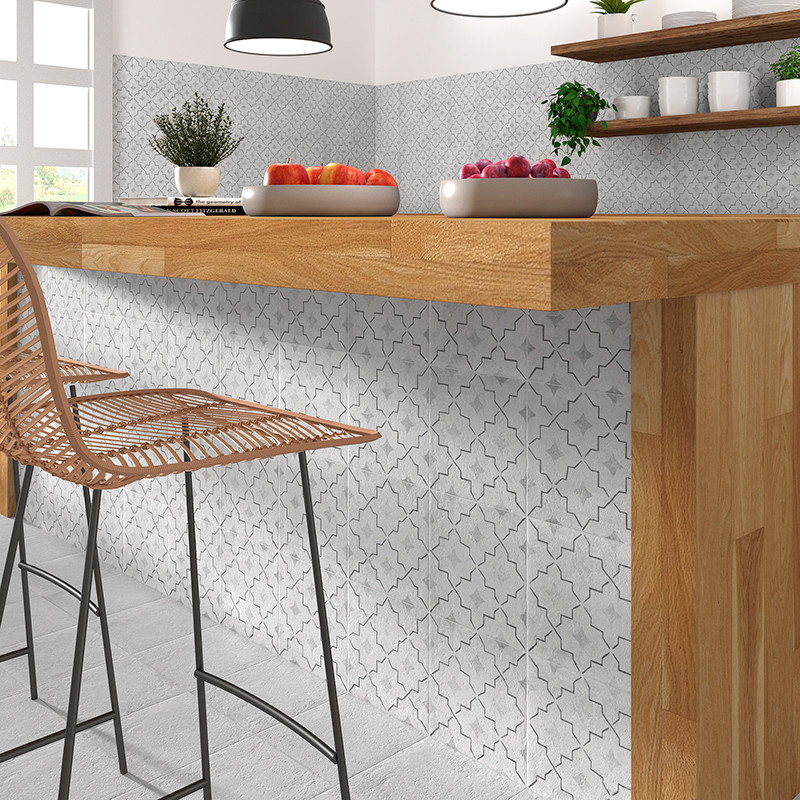 Una encimera de cocina de madera con taburetes se apoya contra una pared de azulejos estampados, rodeada de estantes que contien