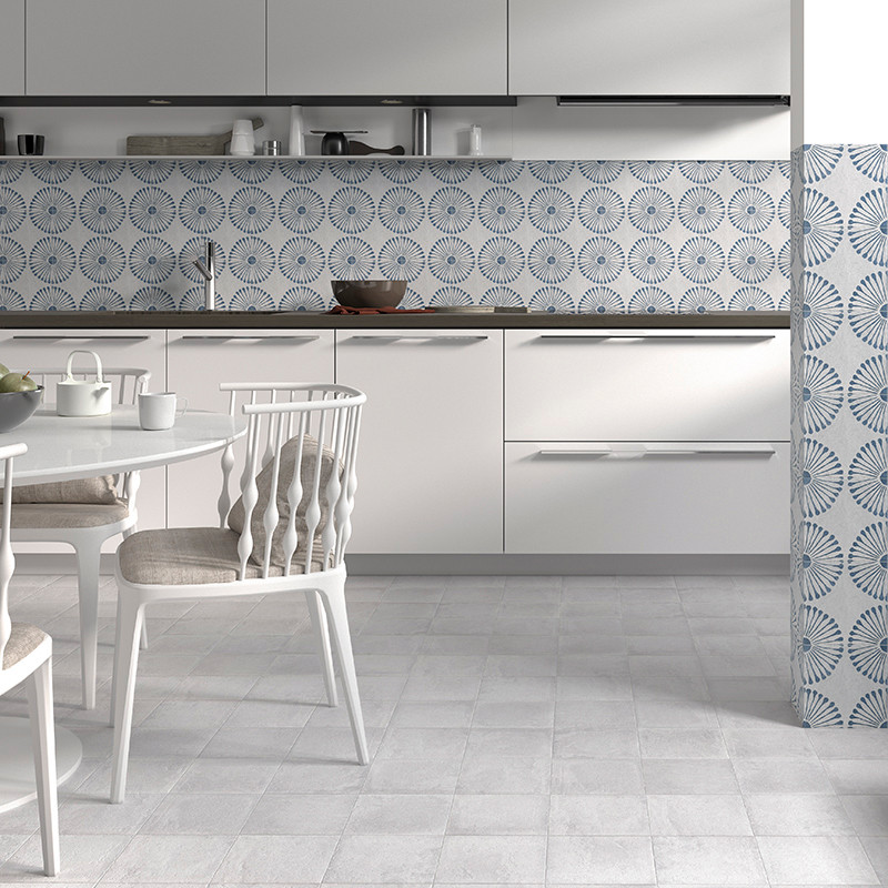 La cocina blanca presenta azulejos azules con diseños circulares como protector contra salpicaduras, con gabinetes y sillas mini