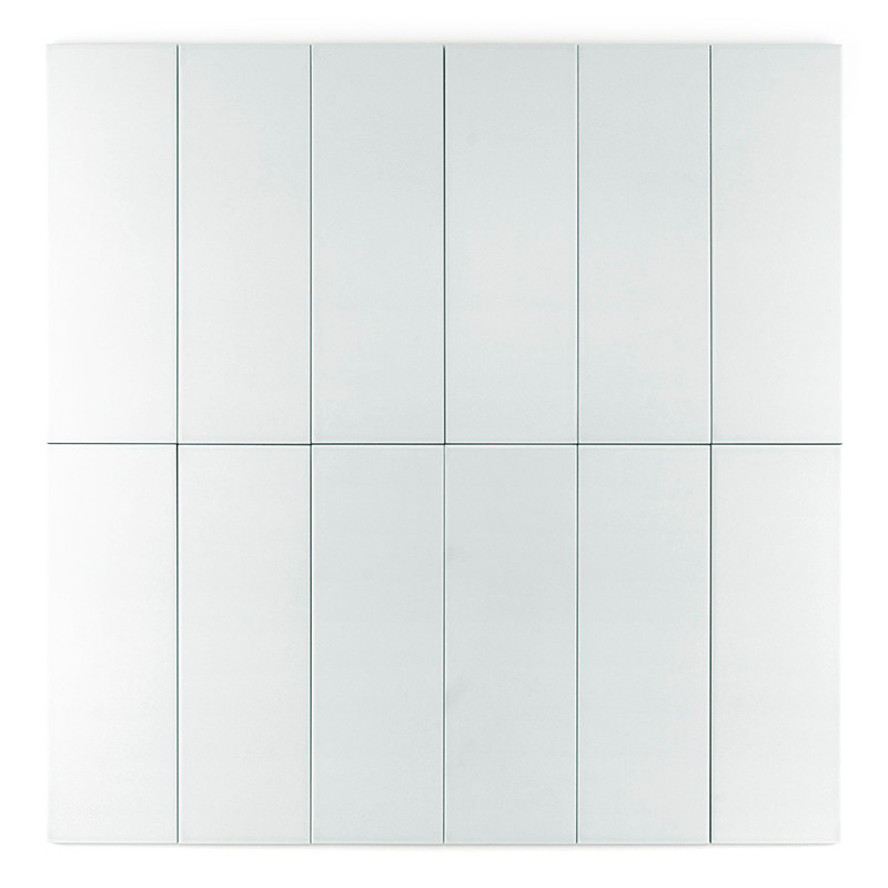 Azulejo blanca rectangular de pie sobre un fondo gris claro y liso.