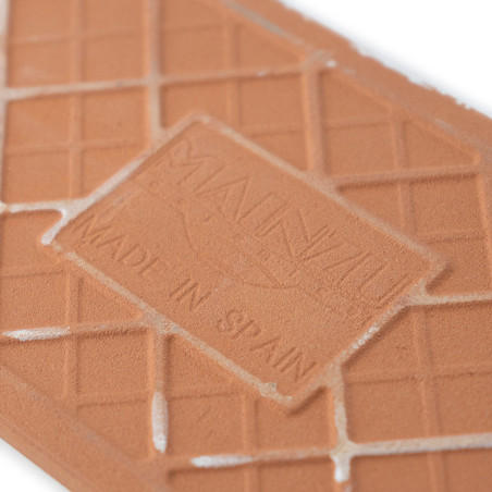 Auf der Terrakottafliese sind „MAUNZU“ und „MADE IN SPAIN“ zu sehen. Die Fliese weist ein geometrisches Gittermuster mit leichte Auf der Terrakottafliese sind „MAUNZU“ und „MADE IN SPAIN“ zu sehen. Die Fliese weist ein geometrisches Gittermuster mit leichte
