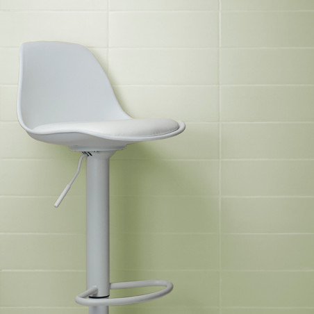Vor einer hellgrün gefliesten Wand steht ein weißer, drehbarer Barhocker mit sichtbarem Hebel, der an ein klares, minimalistisch Vor einer hellgrün gefliesten Wand steht ein weißer, drehbarer Barhocker mit sichtbarem Hebel, der an ein klares, minimalistisch