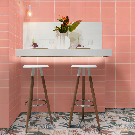 Deux tabourets en bois se dressent sur un comptoir blanc orné d'un vase de fleurs, contre des murs carrelés de roses et des carr Deux tabourets en bois se dressent sur un comptoir blanc orné d'un vase de fleurs, contre des murs carrelés de roses et des carr
