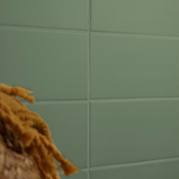 Ein Gitter aus grünen rechteckigen Fliesen bildet eine glatte Wand, die teilweise durch die unscharfe Textur aus braunen, gefloc