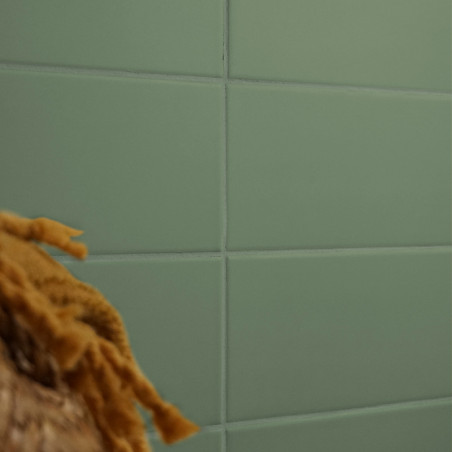 Ein Gitter aus grünen rechteckigen Fliesen bildet eine glatte Wand, die teilweise durch die unscharfe Textur aus braunen, gefloc