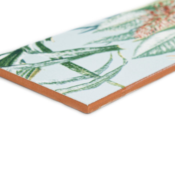 Um azulejo cerâmico exibe um padrão detalhado de folhas tropicais verdes e laranja, contra um fundo branco.