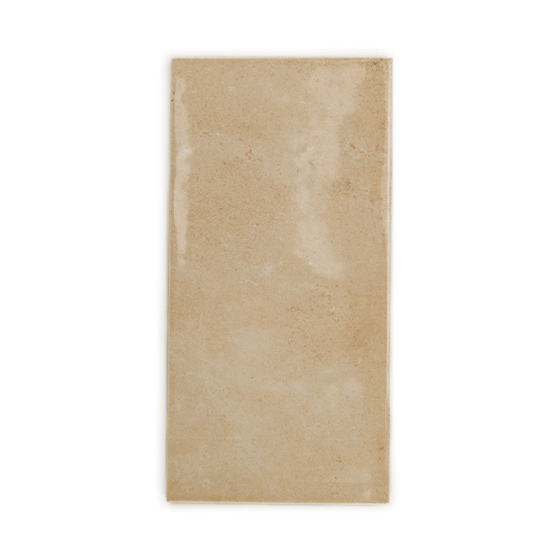 Eine rechteckige beige Fliese mit glatter, glänzender Oberfläche liegt vor einem schlichten weißen Hintergrund.