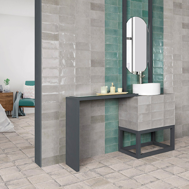 Un baño moderno con azulejos grises y verde azulado cuenta con un elegante lavabo de metal con espejo, con un diseño minimalista