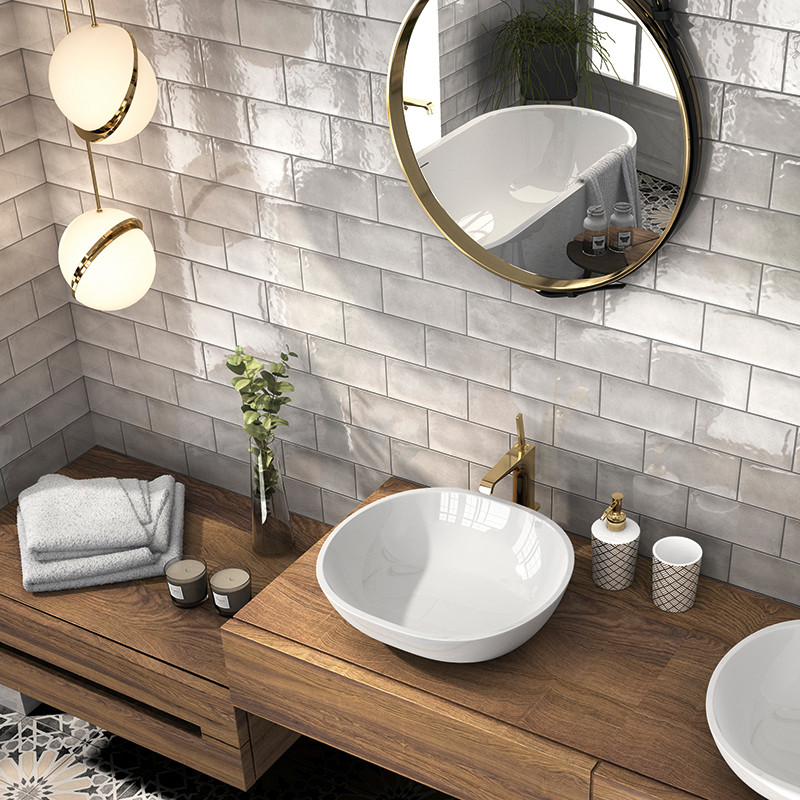 Un lavabo blanco se encuentra sobre un tocador de madera, acompañado de artículos de tocador y toallas. Un espejo redondo reflej