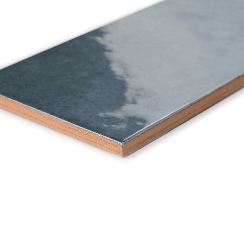 A rectangular ceramic tile with a glossy, reflective surface transitions from dark gray to light gray. shown against a plain whi