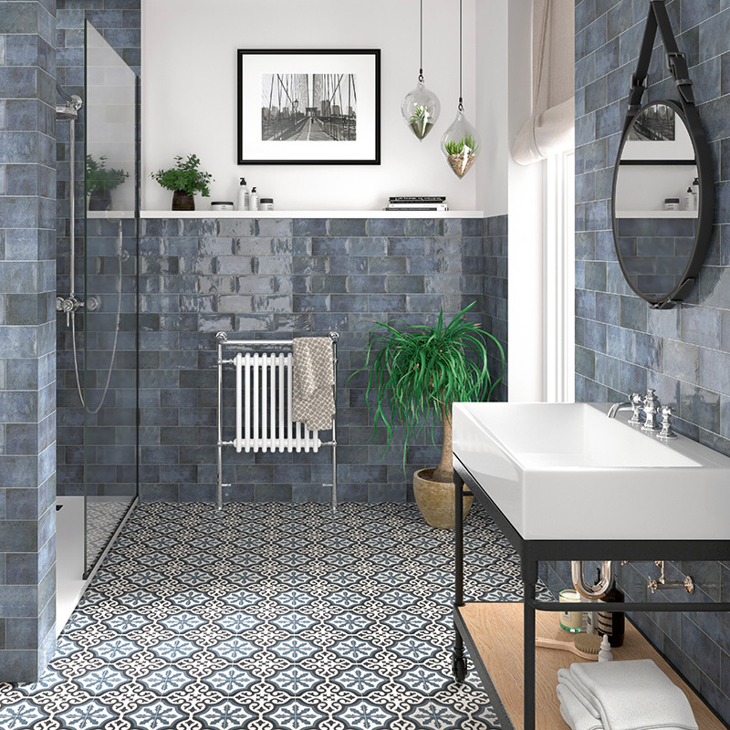 Le lavabo au design élégant se trouve dans une salle de bain avec des carreaux de sol à motifs, des carreaux de mur bleus et des