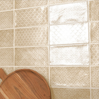 Vierkante keramische tegels vertonen ingewikkelde geometrische patronen. er staat een houten snijplank tegenaan, wat een gezelli