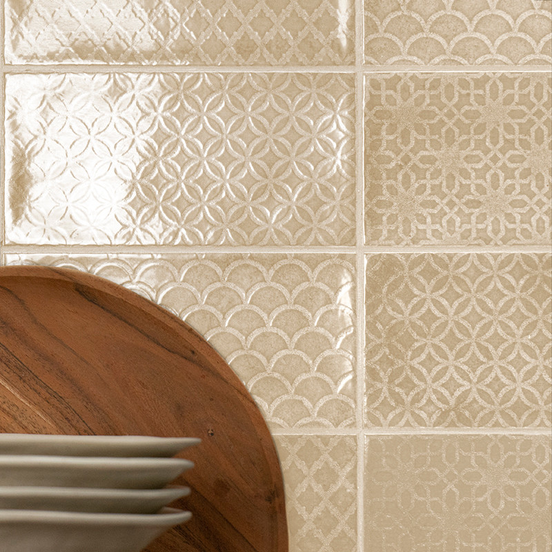 Os ladrilhos cerâmicos exibem padrões geométricos intrincados, refletindo a luz em um ambiente de cozinha. Os pratos ficam sobre