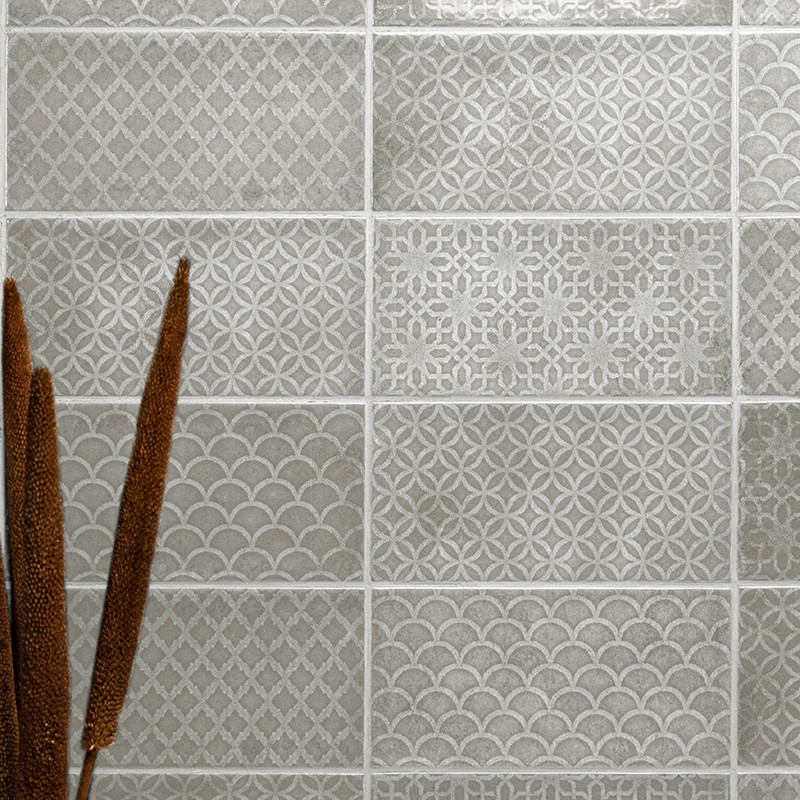Zestien grijze tegels tonen verschillende geometrische patronen. Getextureerde ontwerpen omvatten diamanten, cirkels en schubben
