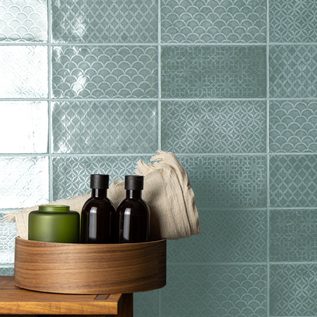 Turquoise tiles feature intricate geometric and scallop patterns. A wooden tray holds bottles and a folded cloth on a wooden sur